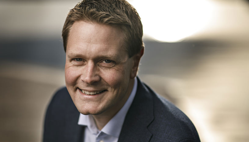 Portrait of a smiling Harald Solberg against a brown backdrop 