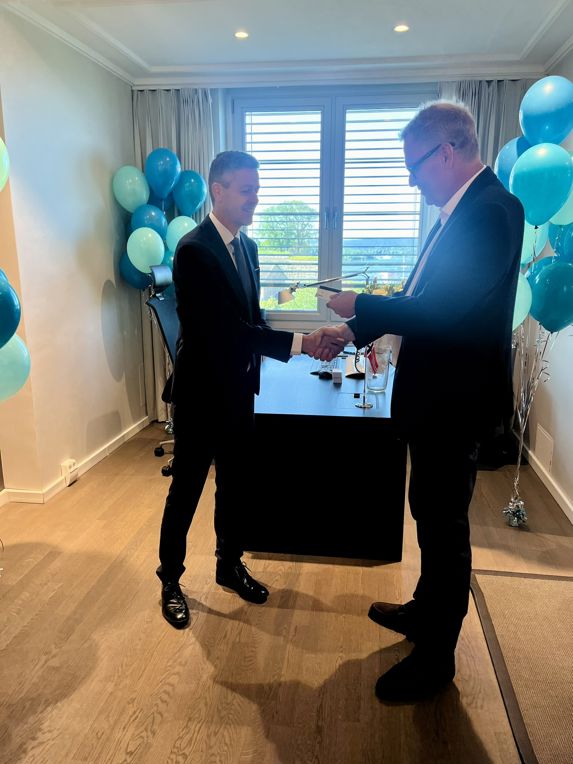 Knut Arild hareide and Viggo Bondi shakes hands in the office, in the background balloons in the colours of the NSA