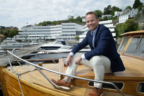 Rolf Thore Roppestad på snekka til oldefar med hovedkontoret til Gard i Arendal i bakgrunnen. 